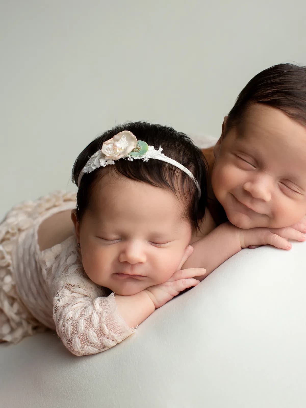 Gemelos recién nacidos en pose boca abajo, uno de ellos sonriendo dormido, durante sesión newborn en Querétaro
