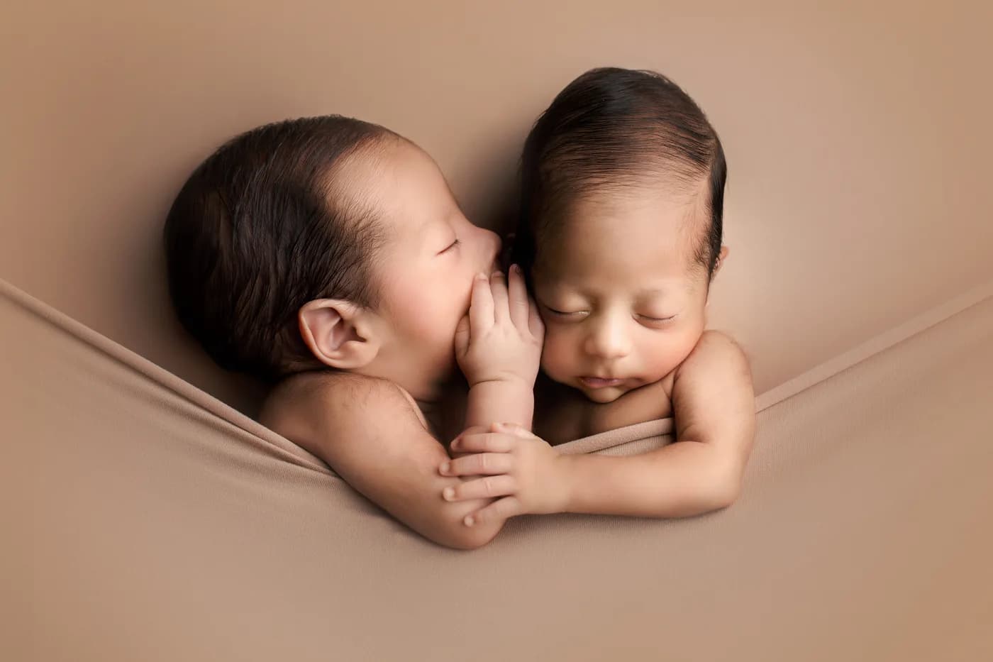 Gemelos recién nacidos frente a frente durante una sesión newborn en Querétaro