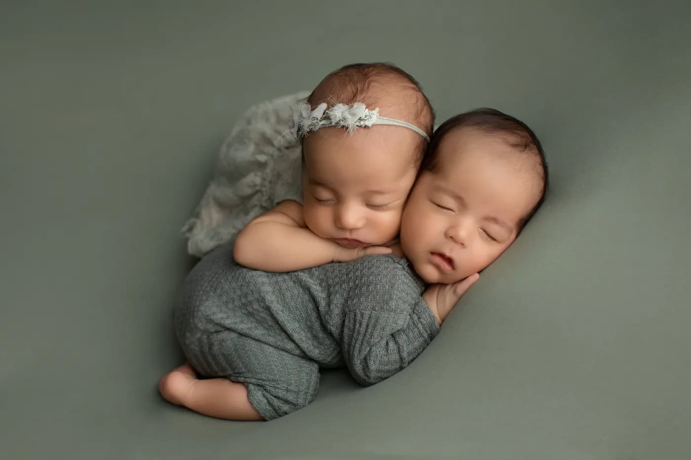 Gemelos recién nacidos abrazados y envueltos en manta gris durante sesión newborn en Querétaro