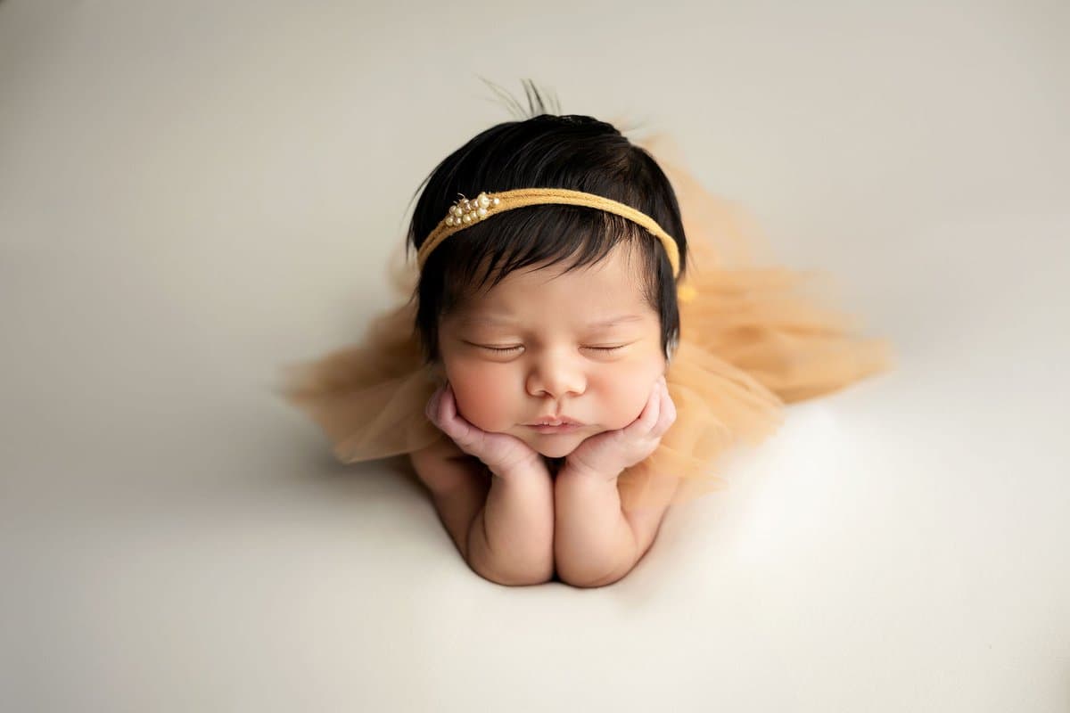 Sesión newborn Querétaro - bebé envuelto en tela blanca con diadema floral